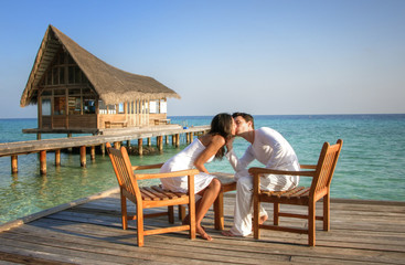 Fototapeta na wymiar Happy love couple sitting on a jetty at the beach (maldives)