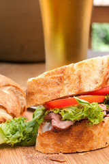 Fresh home-made roast beef sandwich with cold beer .