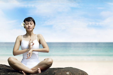 Fototapeta na wymiar Beautiful Asian Woman Meditating at Beach