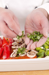 chef spread fresh herbs on lasagna