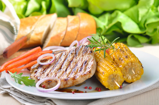 Saftiges Schweinesteak vom Grill mit Maiskolben