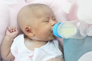 face of infant  drinking mother milk from bottle