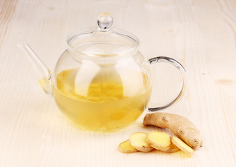Healthy ginger tea in kettle on wooden background