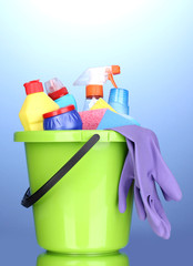 Bucket with cleaning items on blue background
