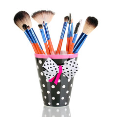 Makeup brushes in a black polka-dot cup isolated on white