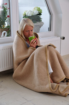 &Auml;ltere Frau mit Tee und Decke  friert