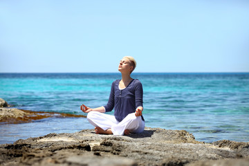 Fototapeta na wymiar Młoda kobieta medytacji na skale