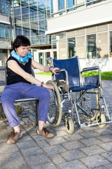 Plakat Woman tries to sit in a wheelchair