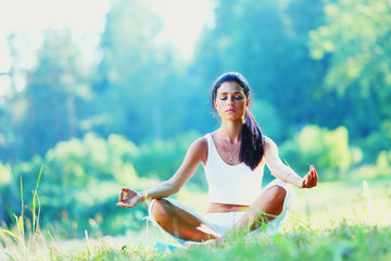 Young woman doing yoga exercise in green park