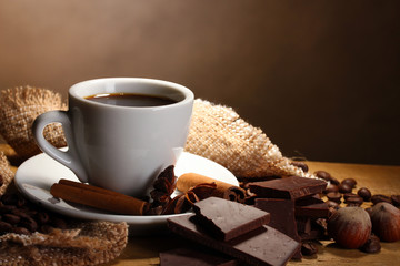 coffee cup and beans, cinnamon sticks, nuts and chocolate