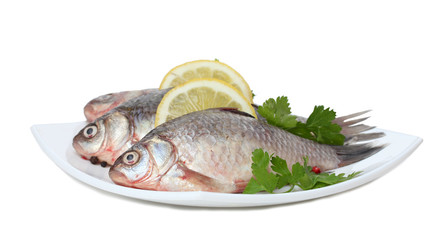Fresh fishes with lemon and parsley on plate isolated on white