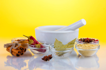 White mortar and pestle with spice on yellow background