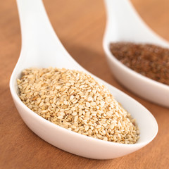Sesame seeds and brown flax seeds on ceramic spoon