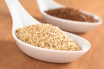 Sesame seeds and brown flax seeds on ceramic spoon