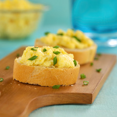 Scrambled eggs on baguette slices with green onion