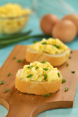 Scrambled eggs on baguette slices with green onion