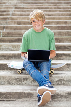 cute teen boy with laptop outdoors