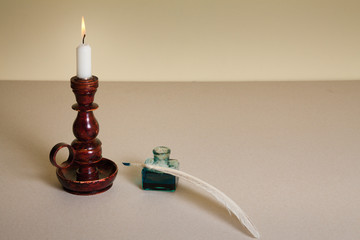 Candle in vintage candlestick, quill and  inkwell