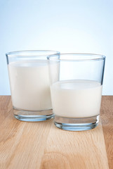 Full and half Glass of fresh milk is on wooden table a blue back