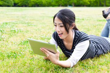 attractive asian woman using tablet computer in the park