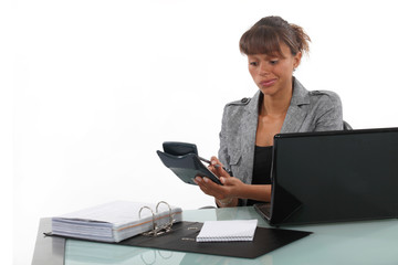 Businesswoman using a calculator at her desk