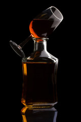 Cognac bottle and glass isolated on black
