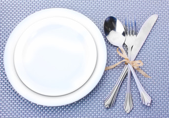 White empty plates with fork, spoon and knife tied with a