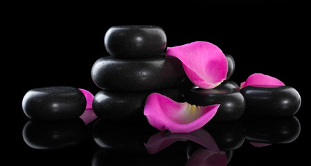 Obraz na płótnie Canvas Spa stones and rose petals on black background