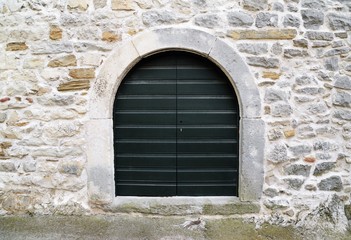 old dark green wooden door on stone wall