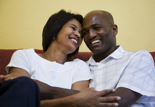 Couple sitting on chouch laughing and cuddling