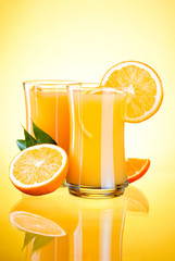 Two Glasses of Fresh Orange juice, half oranges and the leaves o