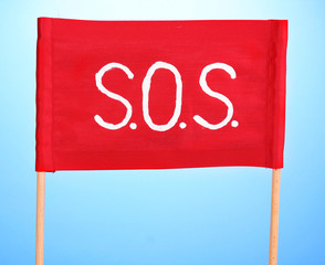 SOS signal written on red cloth on blue background