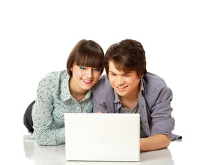 A couple lying on the floor behind a laptop, isolated on white