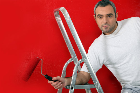 Man Painting Red Wall With Roller Brush