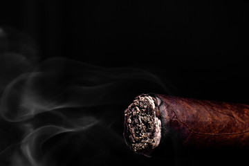 Closeup photo of big brown cigar with ash and smoke
