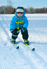 Fototapeta na wymiar Cute little boy skiing downhill