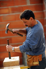 Worker using chisel and hammer on large block of wood