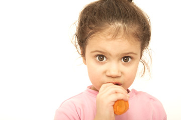 Little girl eating carrot over the white background