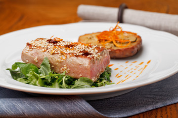 Fried tuna steak and potatoes on the plate