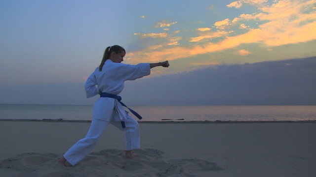 young woman training karate on sunset beach