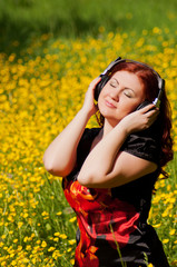 Naklejka na ściany i meble redhead pretty girl with headphones listening to music in nature