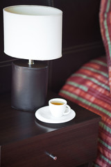 Fototapeta na wymiar bed with a pillow, a cup of tea on the bedside table and lamp