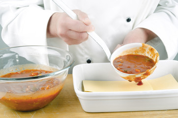 female chef with tomato sauce in a ladle