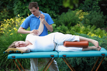 Physical therapist massaging pregnant woman's arm