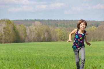 Naklejka na ściany i meble Happy active girl running on green field