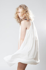 Fototapeta na wymiar Young blonde girl posing in studio in white dress