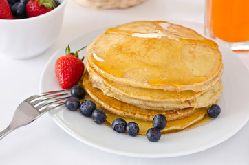 Pile of golden pancakes topped with honey