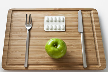Apfel und Tabletten auf Brotzeitbrett
