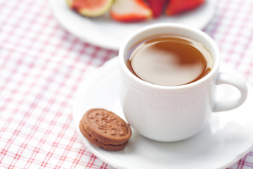 cup of tea,cookie, fig and strawberries on a plate