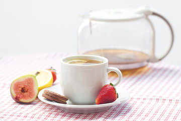 cup of tea,cookie, fig and strawberries on a plate